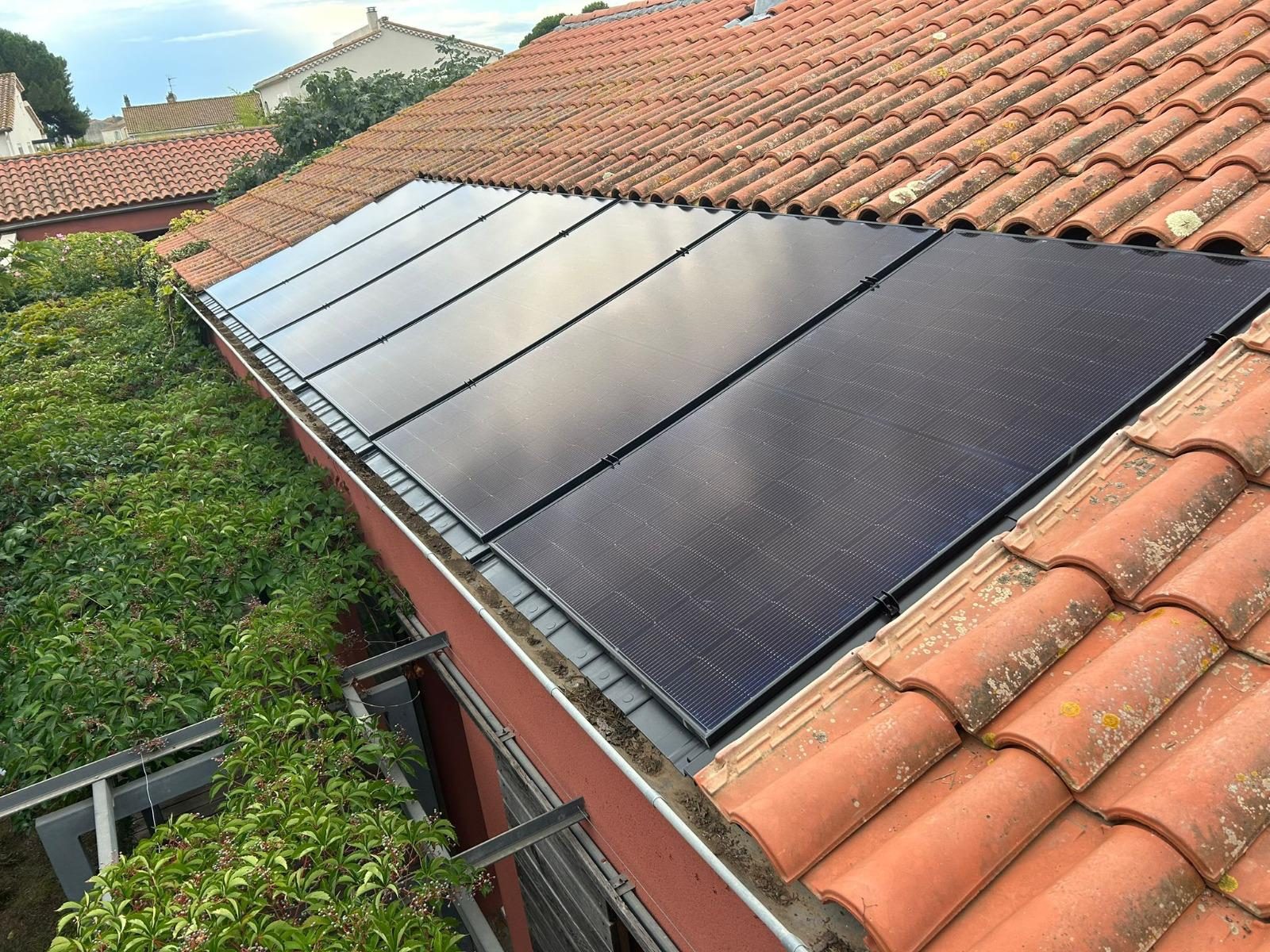 Panneaux solaires alignés sur toiture en tuiles rouges par Nrgie Conseil